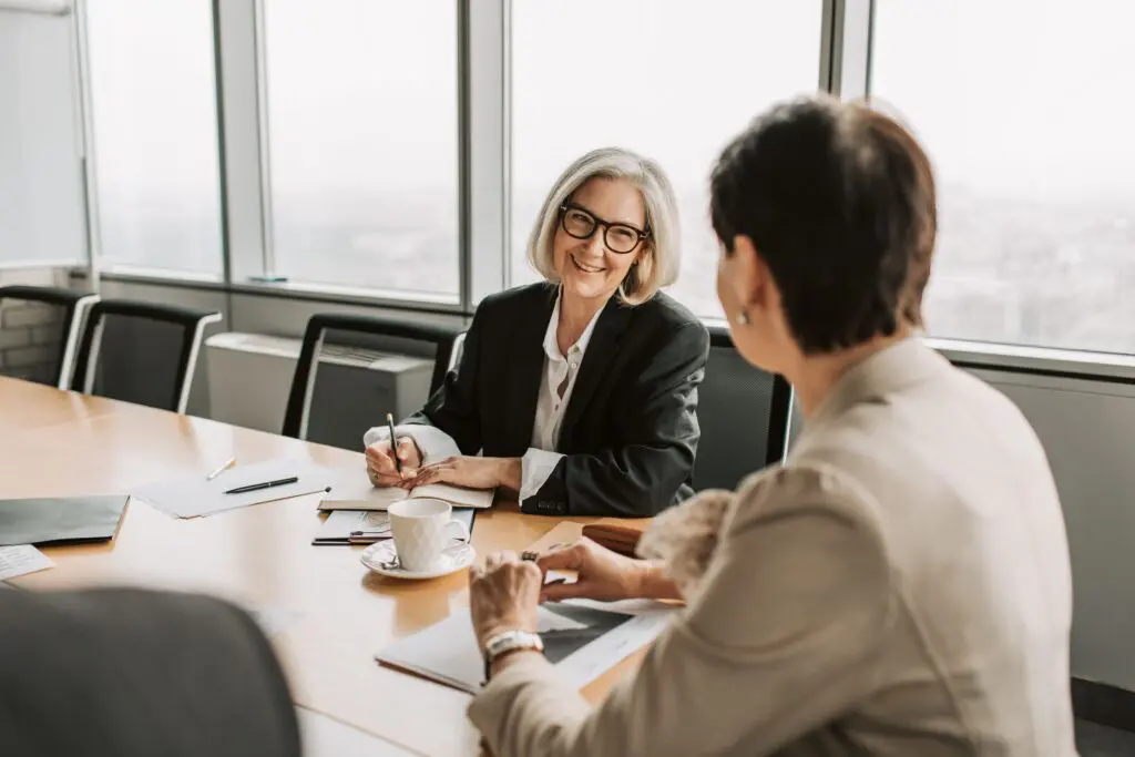 Two women discussing retirement planning in a bright conference room