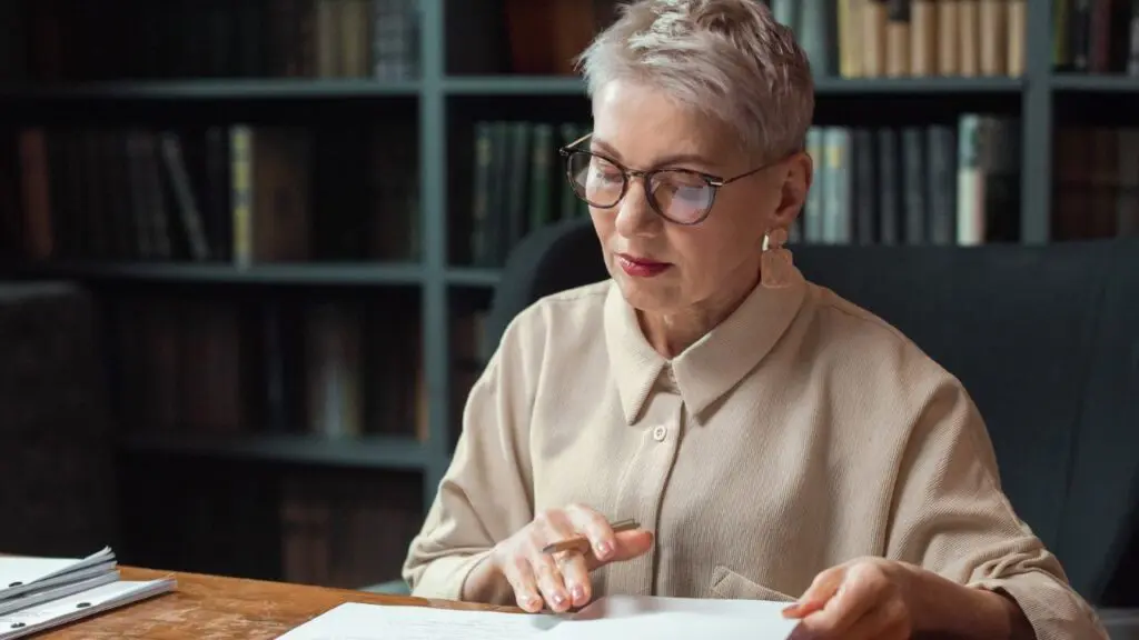 Composed woman in her fifties reviewing her gray divorce financial checklist at a desk