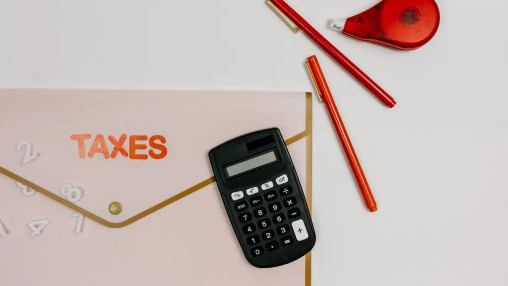 Calculator and red pens beside a folder labeled taxes, representing IRMAA and Medicare premium planning