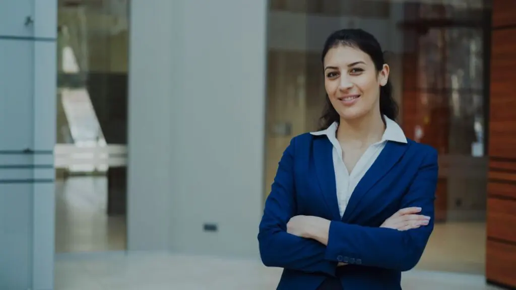 Confident executive woman in a navy suit standing in a modern office lobby during her peak earning years