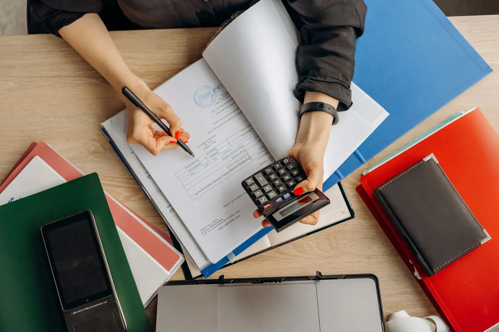 Tax documents, folders, and a calculator on a desk