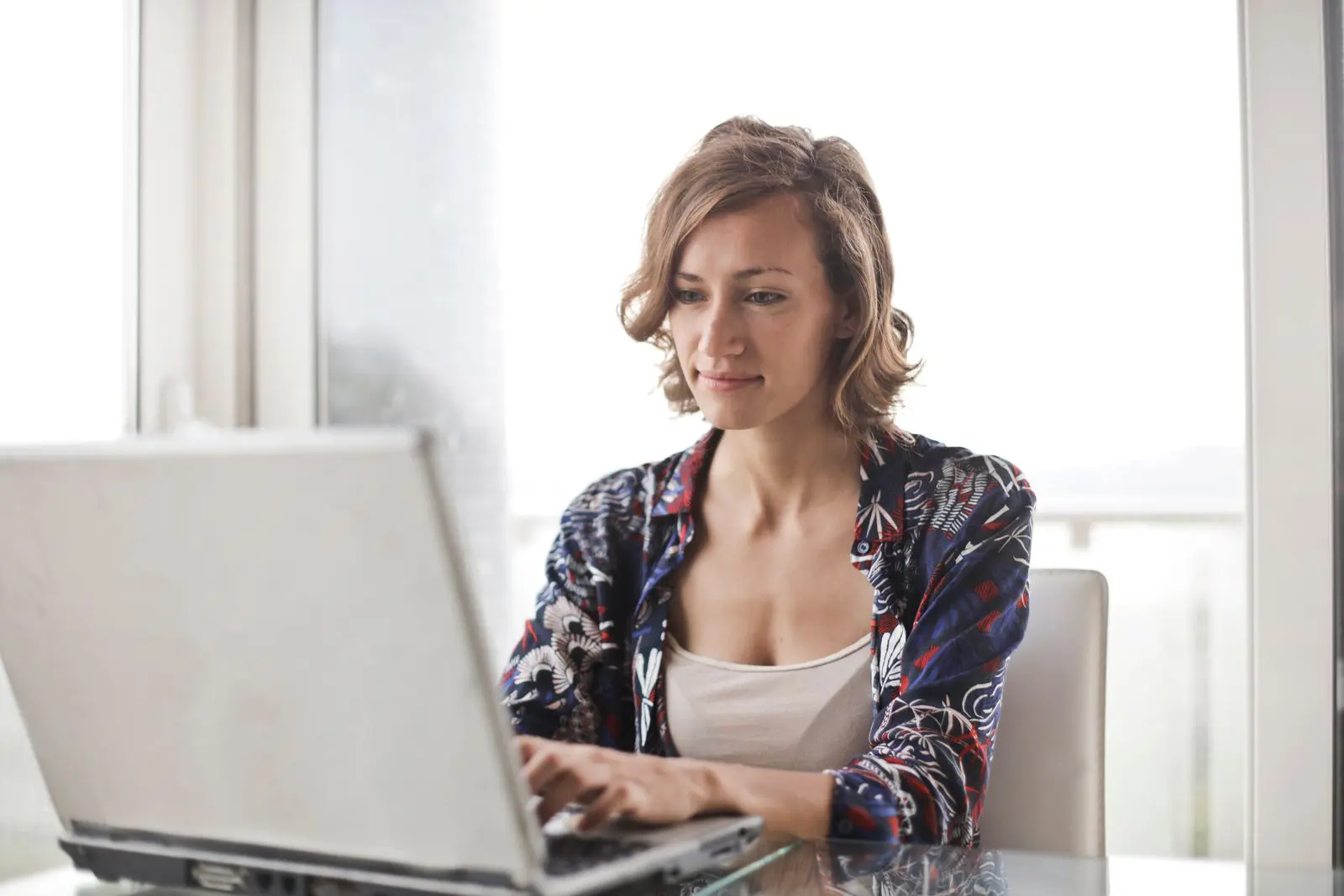 Woman in her 40s working on her retirement plan at a laptop in a bright home office