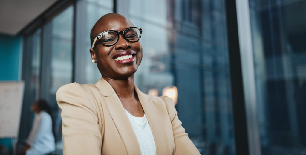 Smiling businesswoman with glasses in a professional setting, showcasing confidence and a positive attitude.