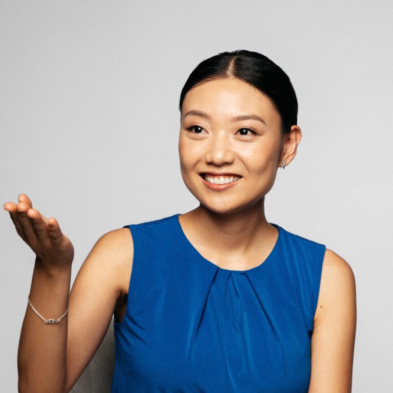 woman with blue shirt asking audience to speak with the hand gesture
