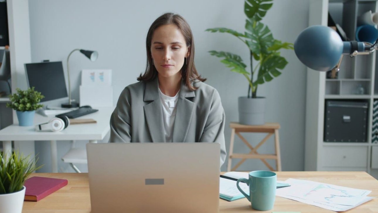 Professional woman working at a desk in a modern office, reviewing her Datadog employee benefits