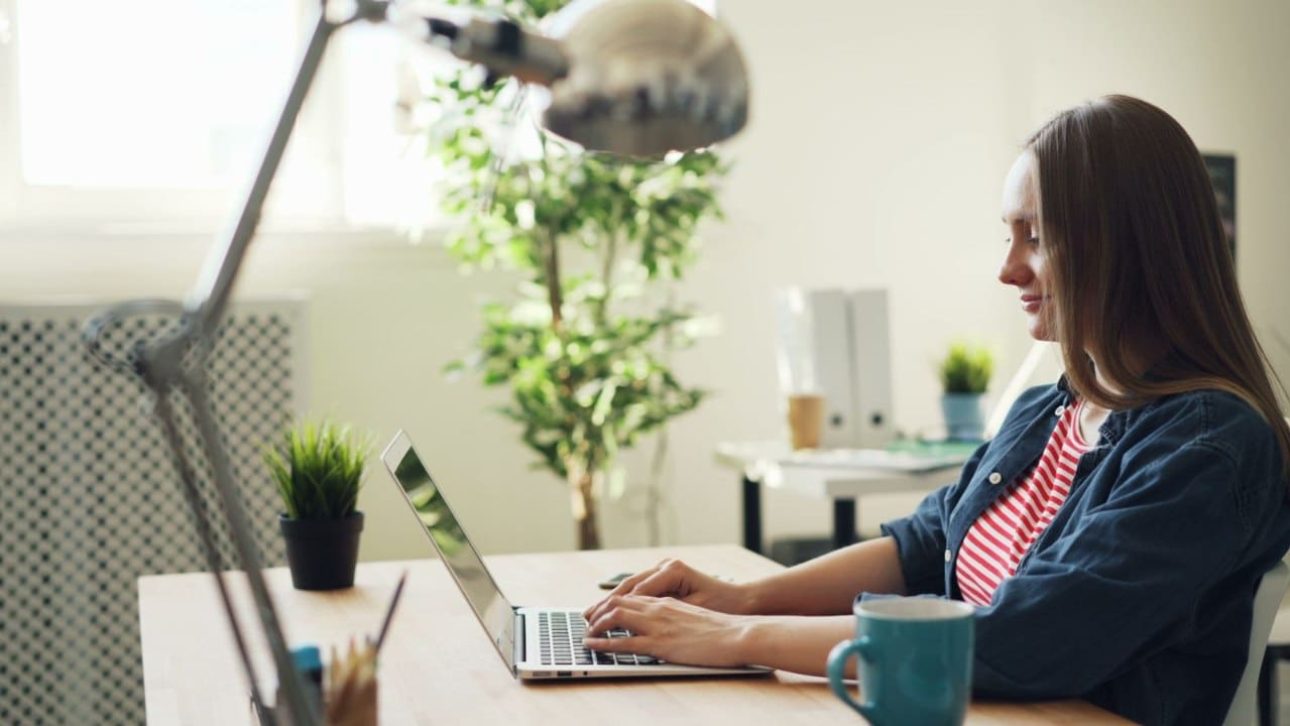 Professional woman working on a laptop in a modern office, reviewing her Google employee benefits