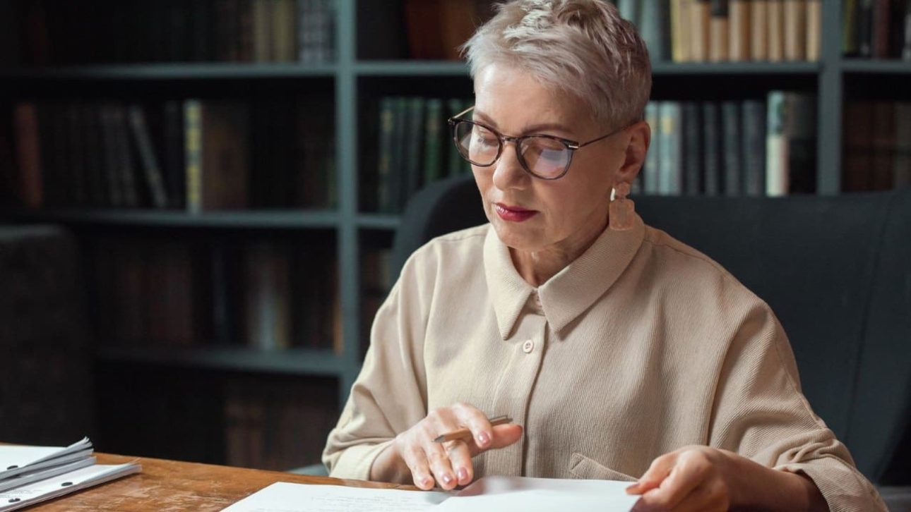 Composed woman in her fifties reviewing her gray divorce financial checklist at a desk