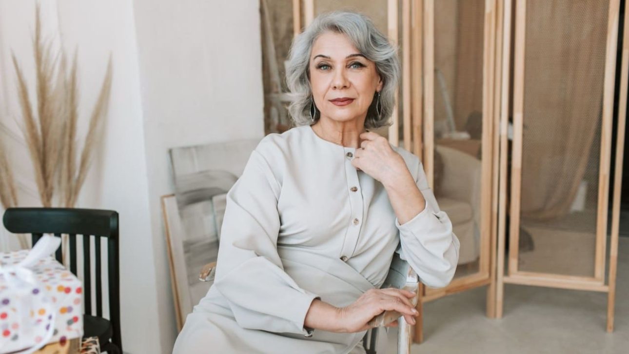 Poised woman in her 60s seated at home, considering how much she needs to retire as a single woman