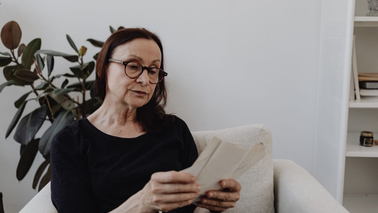 Woman in her 50s reading a life insurance settlement letter at home