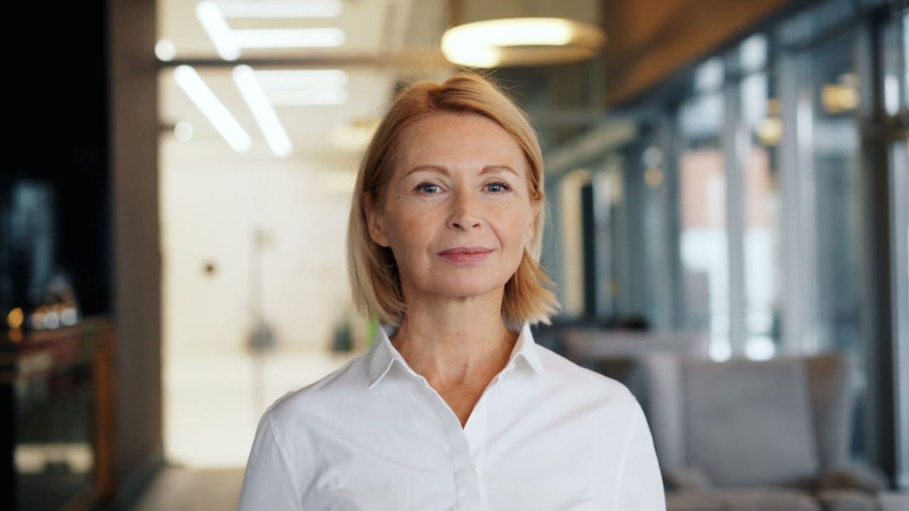 Confident woman in her 50s weighing long-term care insurance options in a modern office