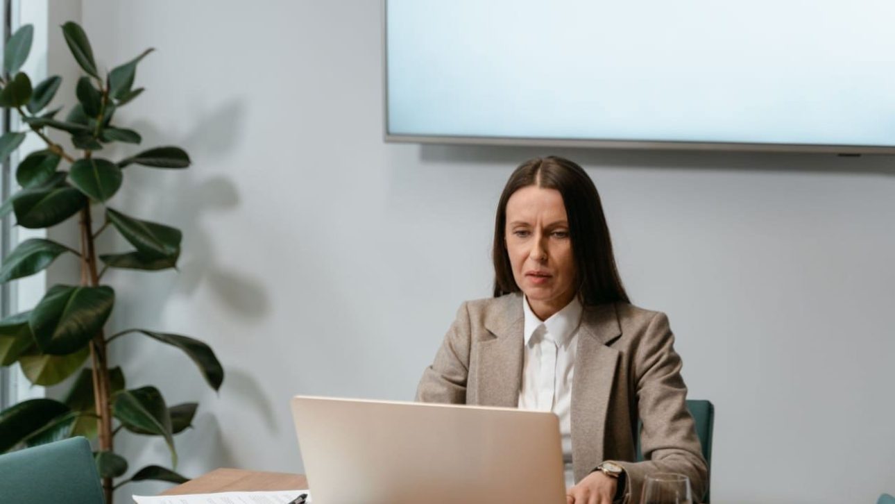 Woman in a business suit reviewing her Novartis employee benefits on a laptop at an office