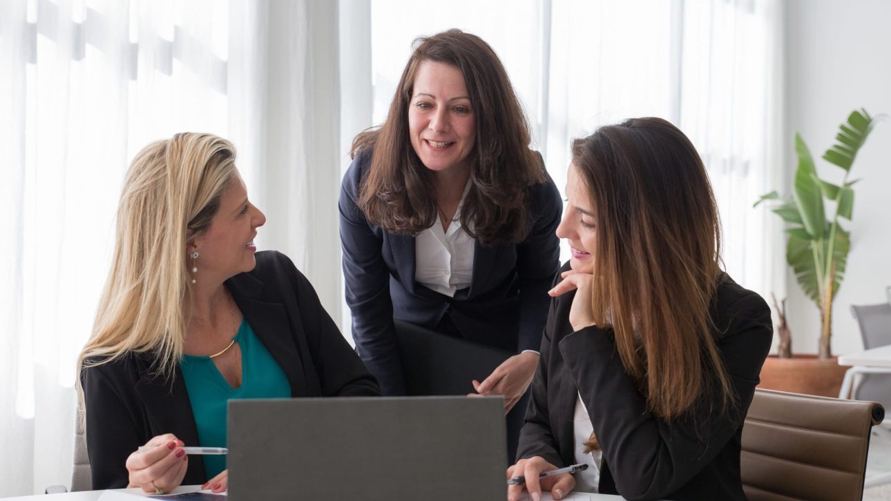 Three women reviewing a financial plan together at a laptop