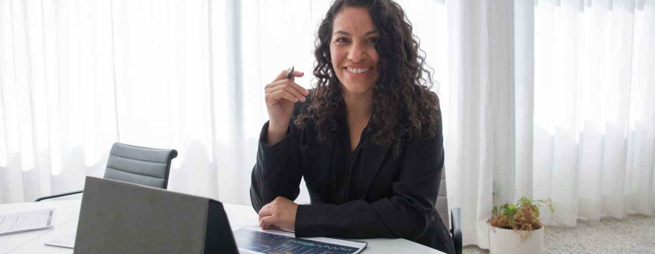 Financial advisor smiling at her desk during a virtual client meeting