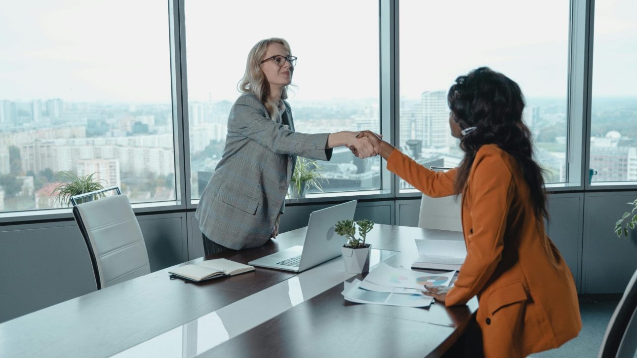 Financial advisor greeting a client in an office overlooking the city