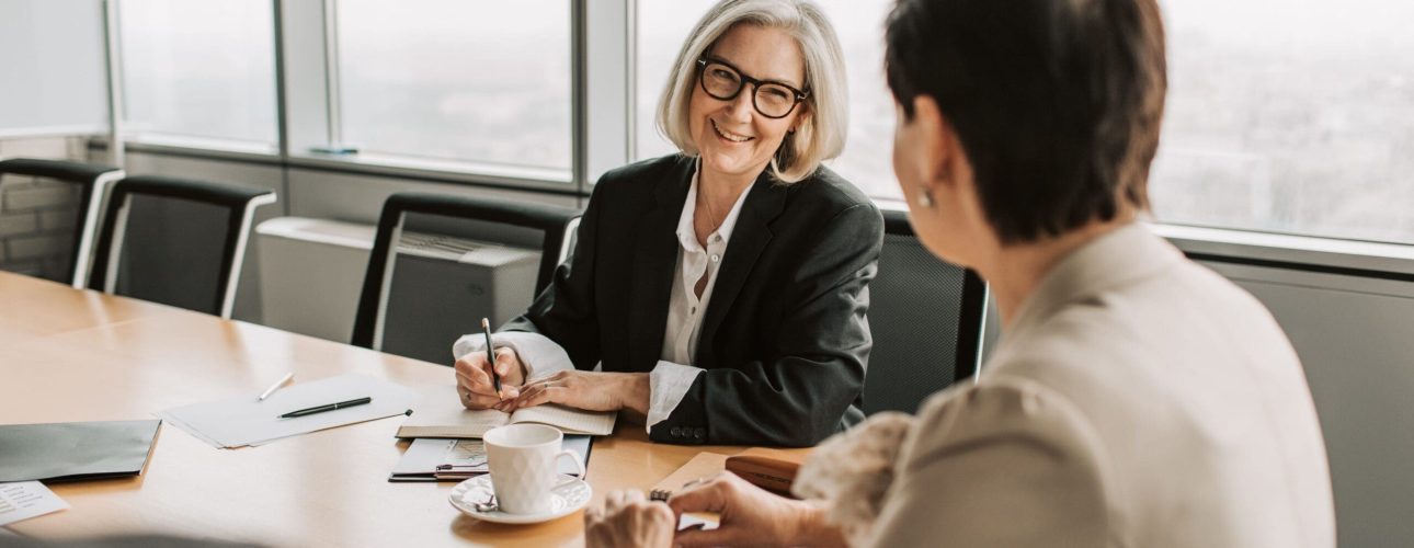 Two women discussing retirement planning in a bright conference room