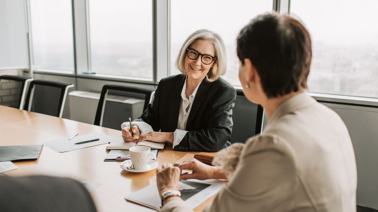 Two women discussing retirement planning in a bright conference room