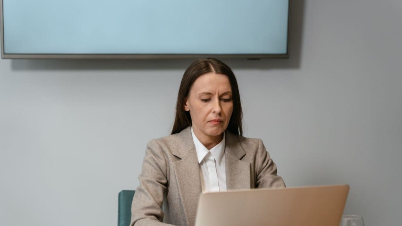 Businesswoman reviewing her Prudential employee benefits on a laptop at an office desk by the window