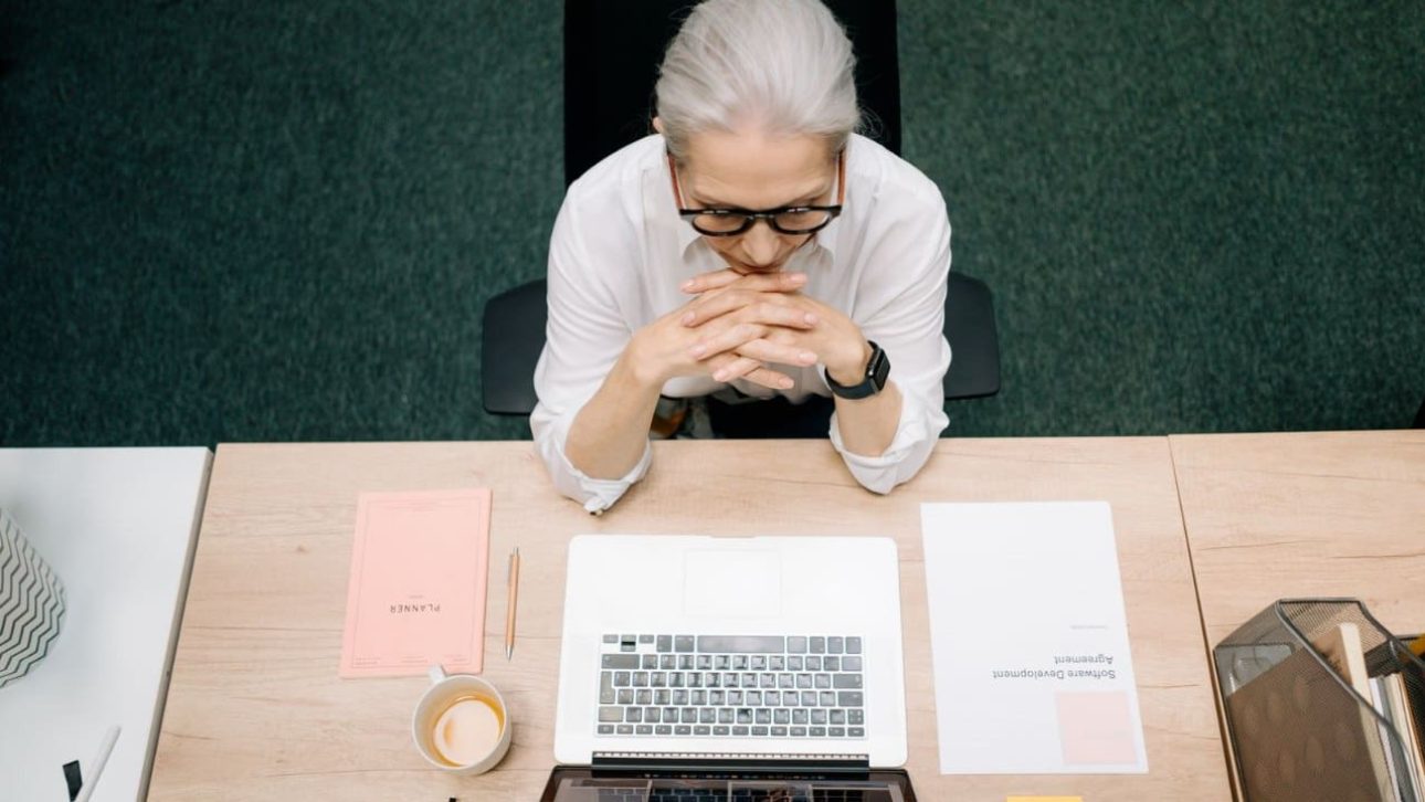 Woman weighing the Roth 401k vs traditional 401k decision at her desk with laptop and notes