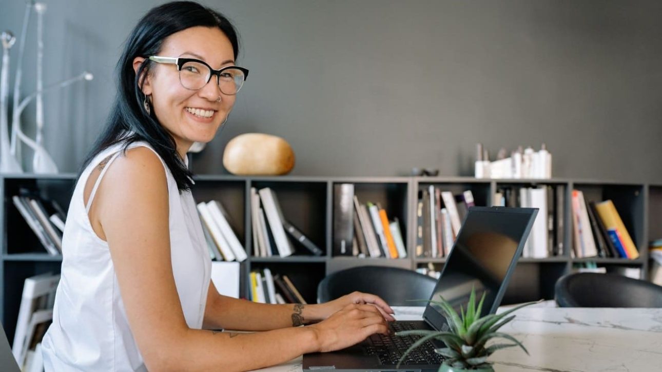 professional woman working on a laptop at a desk in a modern office, reviewing her Salesforce employee benefits