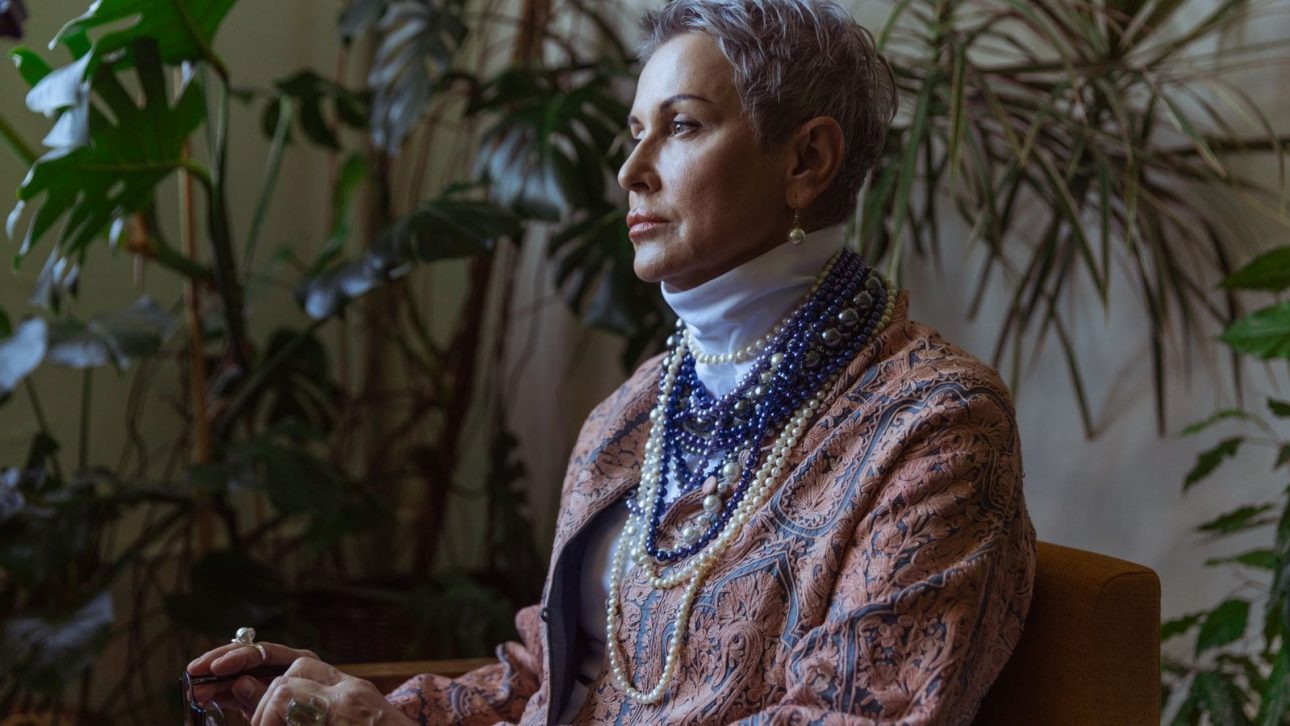 A woman in her 60s sitting thoughtfully at home